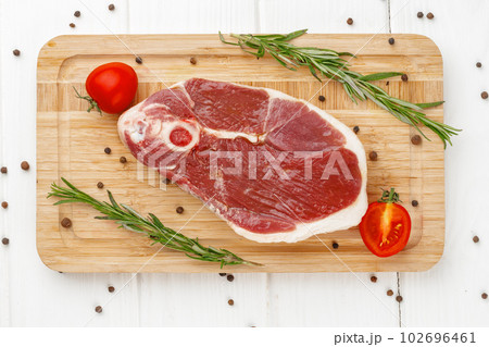Raw lamb steak on board on white wooden table 102696461