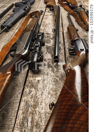 Many hunting rifles on weathered wooden surface Many hunting rifles on weathered wooden surface 102696579