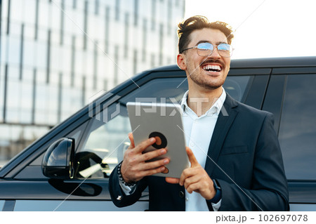 Young businessman using digital tablet while standing outdoors 102697078