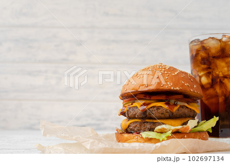 Double cheeseburger served on wooden board against white blurred background 102697134