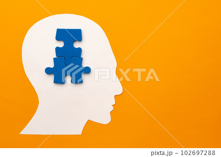 Papercut head silhouette with puzzle pieces on yellow background 102697288