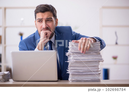 Young male employee and too much work in the office 102698784