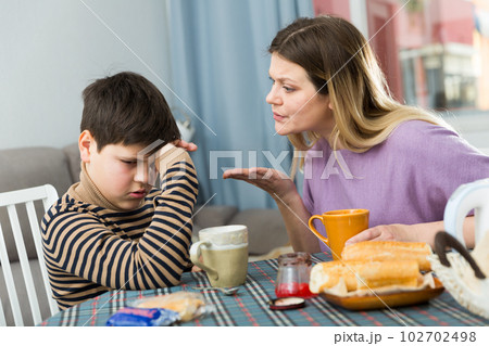 Upset mother and unhappy son arguing during breakfast indoors Upset mother and unhappy son arguing during breakfast indoors 102702498