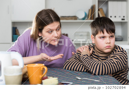 Upset boy and angry mother having quarrel during breakfast at home Upset boy and angry mother having quarrel during breakfast at home 102702894