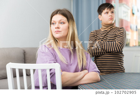 Upset mother sitting at table after arguing with son indoors Upset mother sitting at table after arguing with son indoors 102702905