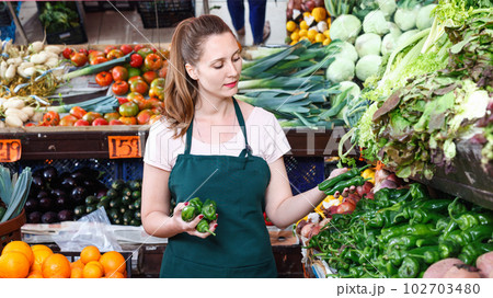 Smiling seller woman is demonstraiting pepper in the market. 102703480