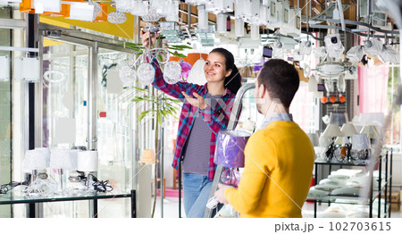 Man and girl are choosing stylish and modern suspended lamp. Man and girl are choosing stylish and modern suspended lamp. 102703615