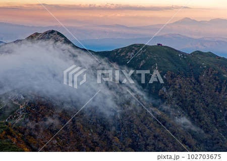 中央アルプス・熊沢岳から見る雲流れる夕暮れの檜尾岳 102703675