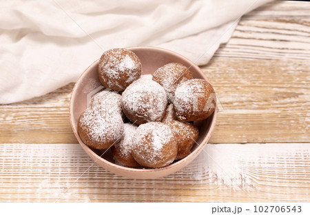 Flatly Paczki Or Zeppole In Pink Bowl With Powdered Sugar On Wooden Table. Fat Thursday Carnival or Tlusty Czwartek, Christian tradition Of Eating Doughnut, Delicious Donuts. Horizontal Plane. 102706543