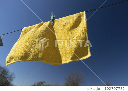 Clothes peg on a towel and washing line against a blue sky Clothes peg on a towel and washing line against a blue sky 102707782