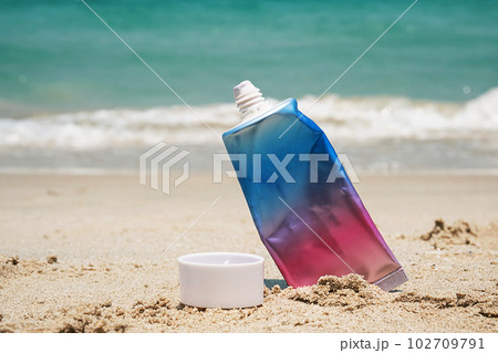 Used cosmetic sunscreen tube on sea shore. 102709791