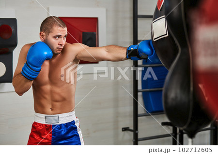boxer man during boxing hitting heavy bag at training fitness gym 102712605