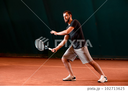Handsome young man in t-shirt holding tennis racket on tennis court 102713625