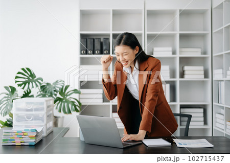 Asian business woman are delighted and happy with the work they do on their tablet, laptop and taking notes at the office. 102715437