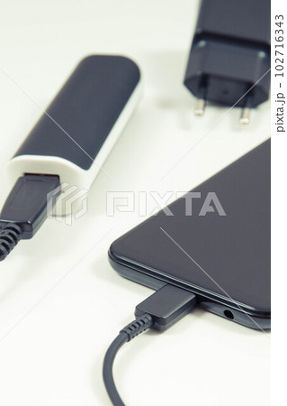 Smartphone with connected powerbank and plug of charger. Telephone charging 102716343