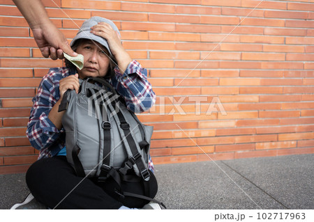 Poor tired stressed depressed elderly Asian woman homeless sitting on the street in the shadow of the building and begging for help and money, Elderly Asian woman abandoned concept 102717963