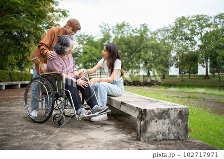 Asian careful caregiver or nurse taking care of the patient is hurting knee in wheelchair. Concept of happy retirement with care from caregiver and Savings and senior health insurance, a Happy family 102717971