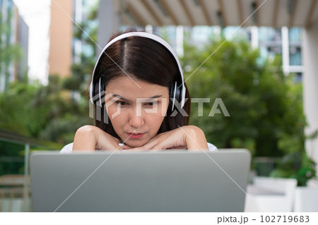Portrait of a cheerful young attractive Asian woman listening music and using laptop computer for working online. Distance learning online education and work via the internet. Successful people Portrait of a cheerful young attractive Asian woman listening music and using laptop computer for working online. Distance learning online education and work via the internet. Successful people 102719683