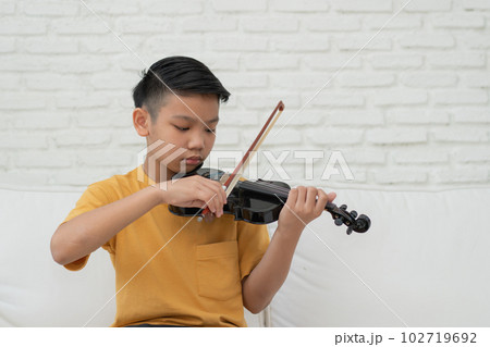 A Little Asian kid playing and practice violin musical string instrument against in home, Concept of Musical education, Inspiration, Teenager art school student. A Little Asian kid playing and practice violin musical string instrument against in home, Concept of Musical education, Inspiration, Teenager art school student. 102719692