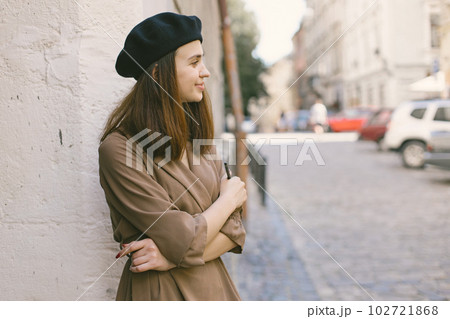 Female painter painting in the city. A woman wearing khaki dress and a black hat. Girl thinking about future paintings. 102721868