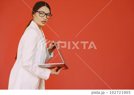 Woman in a studio. Lady with a laptop. Brunette in a white suit. Woman in a studio. Lady with a laptop. Brunette in a white suit. 102721905