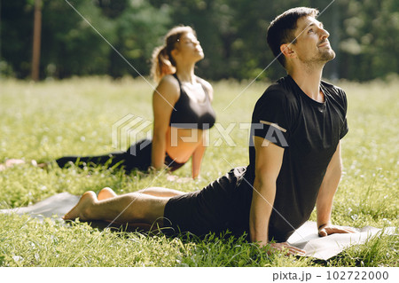 Young sportive couple doing yoga fitness . People in a summer park. Young sportive couple doing yoga fitness . People in a summer park. 102722000