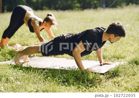Young sportive couple doing yoga fitness . People in a summer park. 102722035