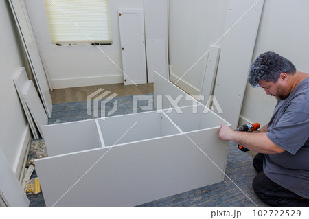 Carpenter was in process of assembling furniture closet cabinet that needed to be installed Carpenter was in process of assembling furniture closet cabinet that needed to be installed 102722529