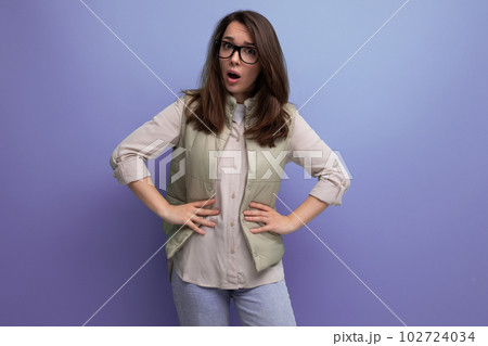 portrait of a well-groomed young brunette woman correcting her eyesight using glasses on a studio 102724034