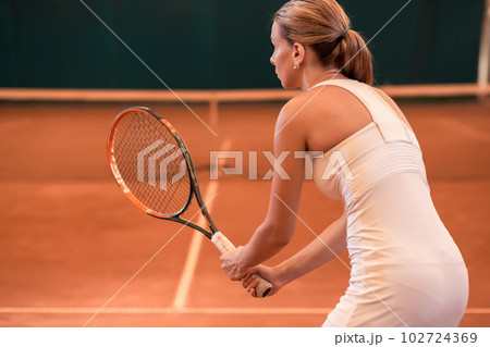View from the back on a female tennis player on a court indoor 102724369