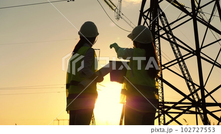 electrical engineers work with tablet laptop computer. tower voltage sun. silhouette engineer work. vutouristic development concept tower energy. wet mains voltage. architect investor construction electrical engineers work with tablet laptop computer. tower voltage sun. silhouette engineer work. vutouristic development concept tower energy. wet mains voltage. architect investor construction 102727553
