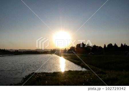 写真　田植えの準備の水張り　太陽が沈み水鏡の田んぼに映る　水鏡のような田んぼの田植えの準備 102729342