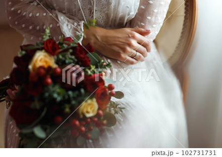 Details of wedding day. Bride in elegant white dress holds a wedding bouquet of flowers in hands. Details of wedding day. Bride in elegant white dress holds a wedding bouquet of flowers in hands. 102731731