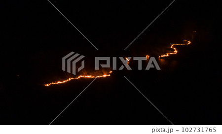 Night fire in the forest with fire and smoke.Epic aerial photo of a smoking wild flame.A blazing,glowing fire at night.Forest fires.Dry grass is burning. climate change,ecology.Line fire in the dark. Night fire in the forest with fire and smoke.Epic aerial photo of a smoking wild flame.A blazing,glowing fire at night.Forest fires.Dry grass is burning. climate change,ecology.Line fire in the dark. 102731765