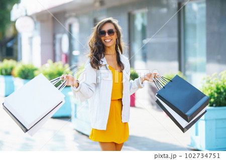 Fashion woman with shopping bags walking on street. Spring Style. Consumerism, shopping, lifestyle. Fashion woman with shopping bags walking on street. Spring Style. Consumerism, shopping, lifestyle. 102734751