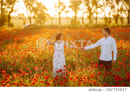 Loving couple in the poppy field at sunset. Enjoying time together. love and lifestyle. 102735657