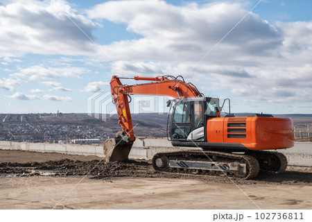 Yellow excavator on a construction site against blue sky 102736811