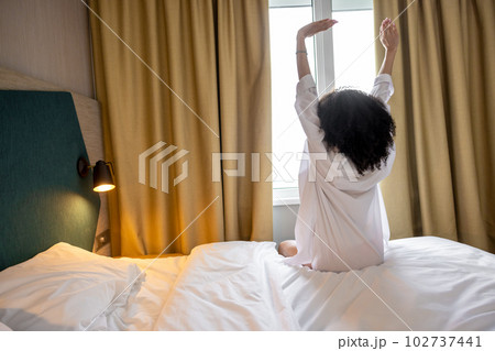 Pretty curly-haired woman in white bathrobe in a hotel in the morning 102737441