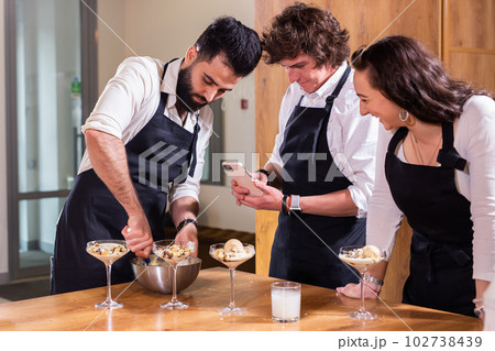 Chef teaching trainees how to make ice cream. Cooking tasty ice cream dessert made from chocolate and vanilla in glass bowl 102738439