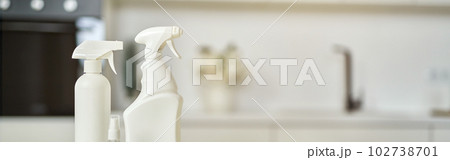 Cleaning set. Detergent bottles, stack of rugs and protective rubber gloves on surface in the kitchen 102738701
