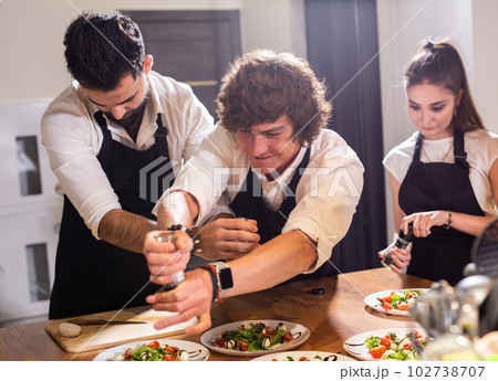 Funny Chef sprinkles with paprika over caprese salad in restaurant kitchen Funny Chef sprinkles with paprika over caprese salad in restaurant kitchen 102738707