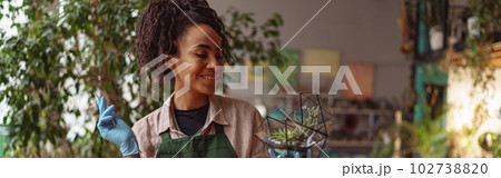 Happy smiling woman florist making succulent plant composition at floral design studio 102738820