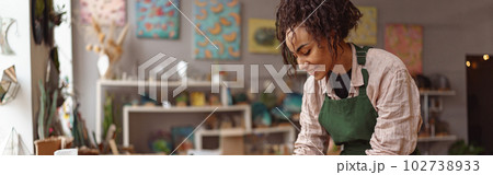 Smiling woman decorator making green ikebana on tray with epoxy resin in florist workshop 102738933