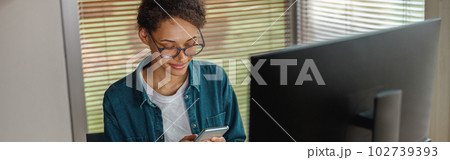 Smiling woman interior designer holding smartphone during break at home office. Freelance concept Smiling woman interior designer holding smartphone during break at home office. Freelance concept 102739393