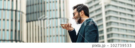 Indian Businessman with laptop recording audio message to client standing near office during break 102739533