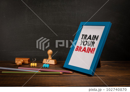 Train Your Brain. Picture frame with text on wooden office table 102740870