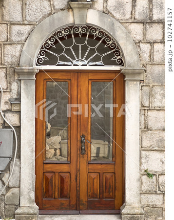 Arched wooden front door in an old stone building Arched wooden front door in an old stone building 102741157