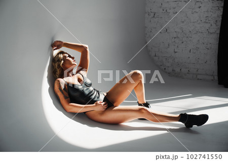 a sexy blonde with tattoos in a leather swimsuit and boots. a sexy blonde with tattoos in a leather swimsuit and boots. 102741550