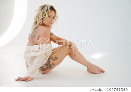a gentle naked blonde woman in a white shirt on the floor. a gentle naked blonde woman in a white shirt on the floor. 102741580