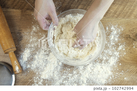 Top view of female hands kneading dough for baking. The concept of making yeast dough. 102742994